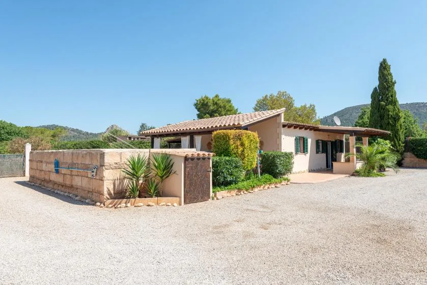 A single-story house with a tiled roof stands beside a gravel driveway.
