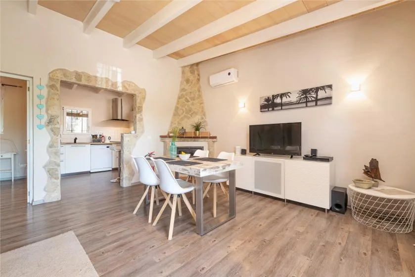 A dining and living area with a table, seating, and a television.