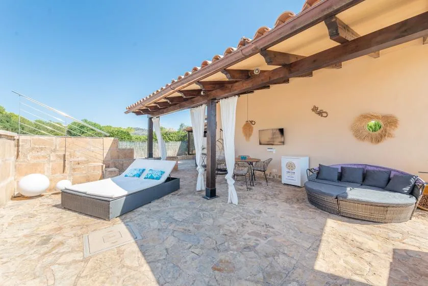 A sunny outdoor patio with cushioned seating, a daybed, and a covered dining area.