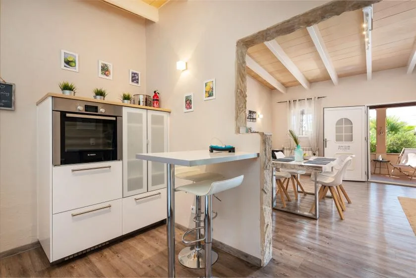 A bright kitchen and dining area with a counter and a table beside glass doors.