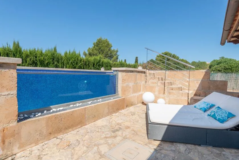 A sunny outdoor terrace features a small blue pool and cushioned seating.
