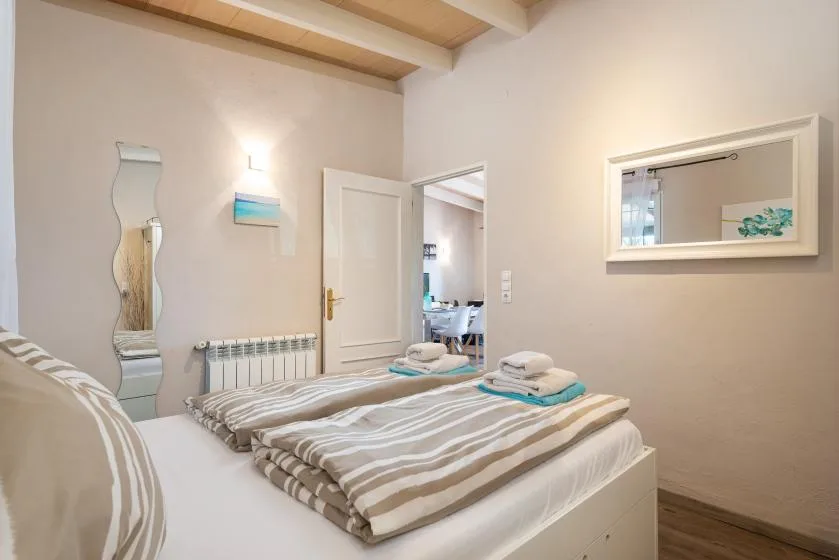 A bedroom with striped bedding and an open doorway leading to a bathroom.