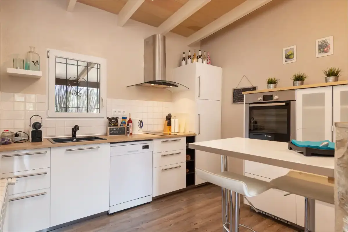 A bright kitchen with white cabinets, a cooktop, and a central island.