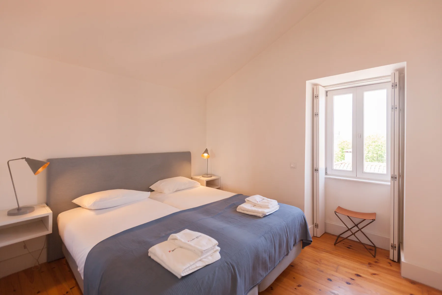 A bedroom with a double bed, bedside tables, and a bright window.