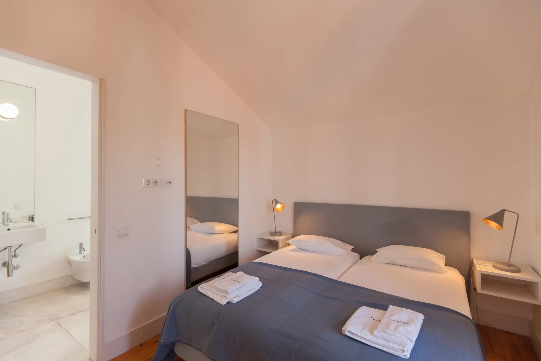 A bedroom with a double bed, bedside tables, and an open doorway to a bathroom.
