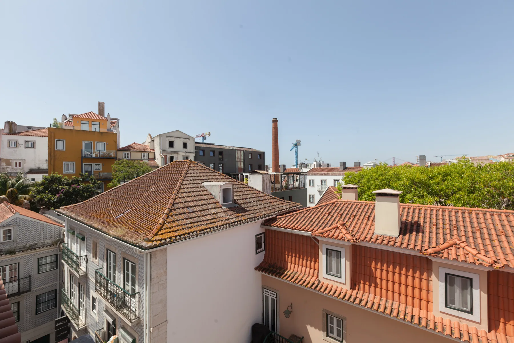 Rooftops and residential buildings fill the view beneath a clear sky.