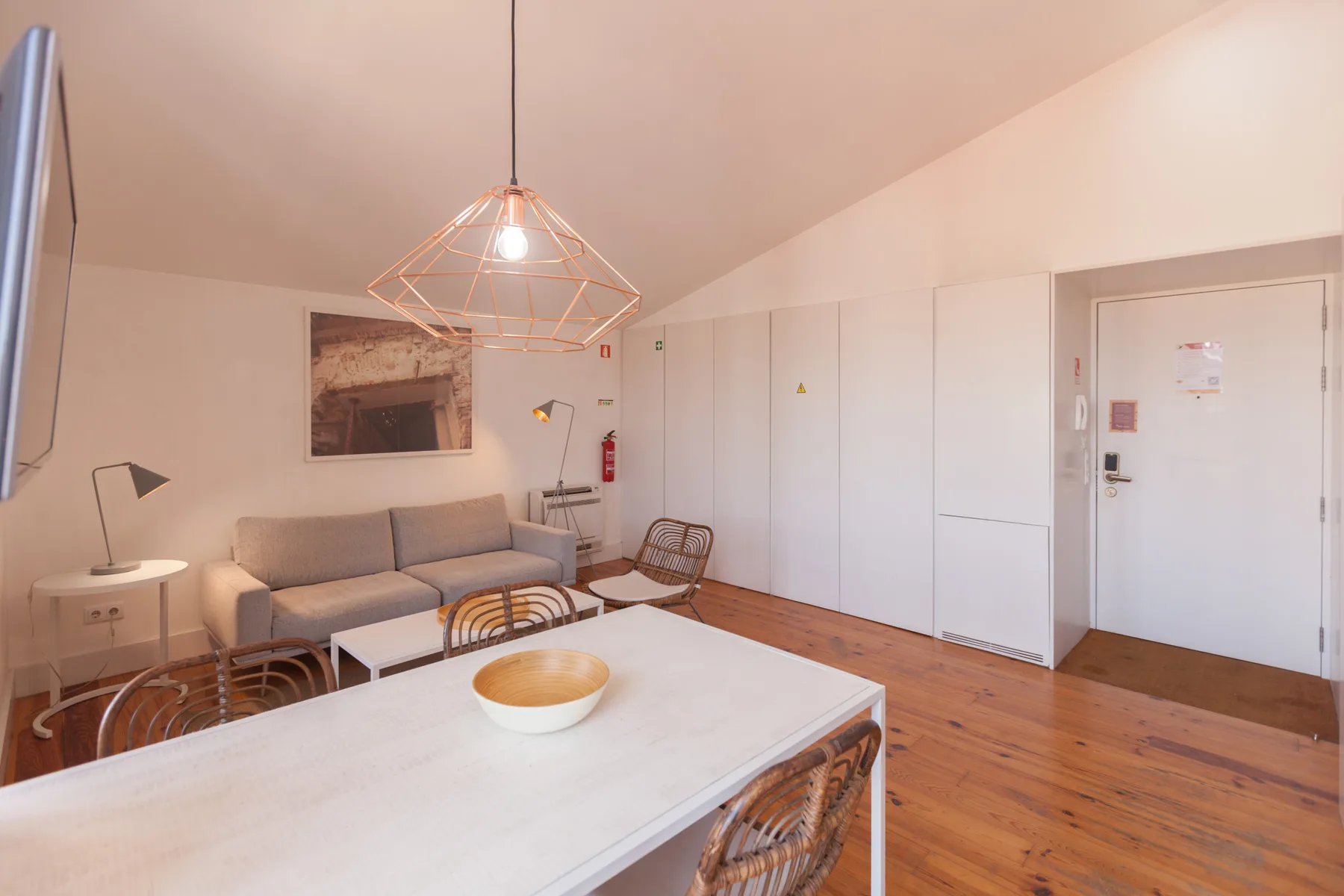 A bright living and dining area with a sofa, table, and pendant light.