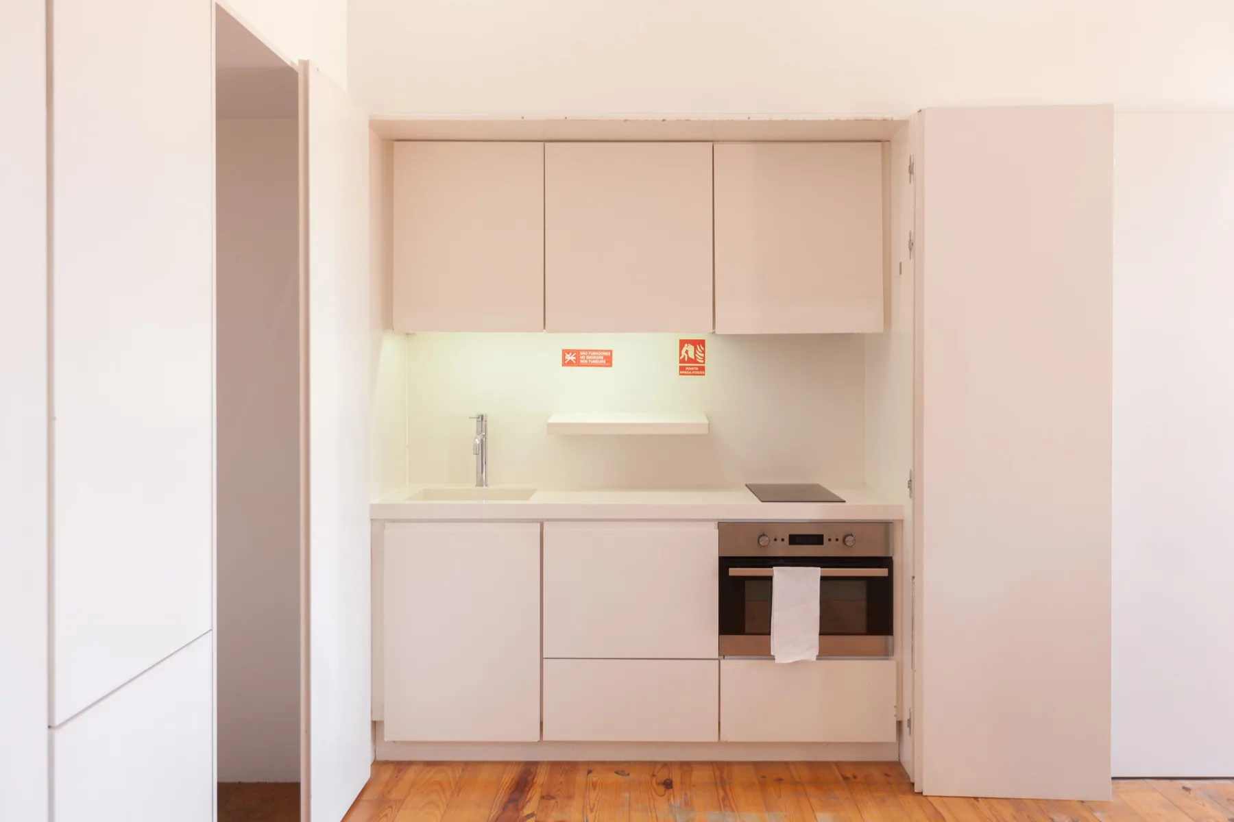 A compact kitchen with pale cabinets and a built-in oven.