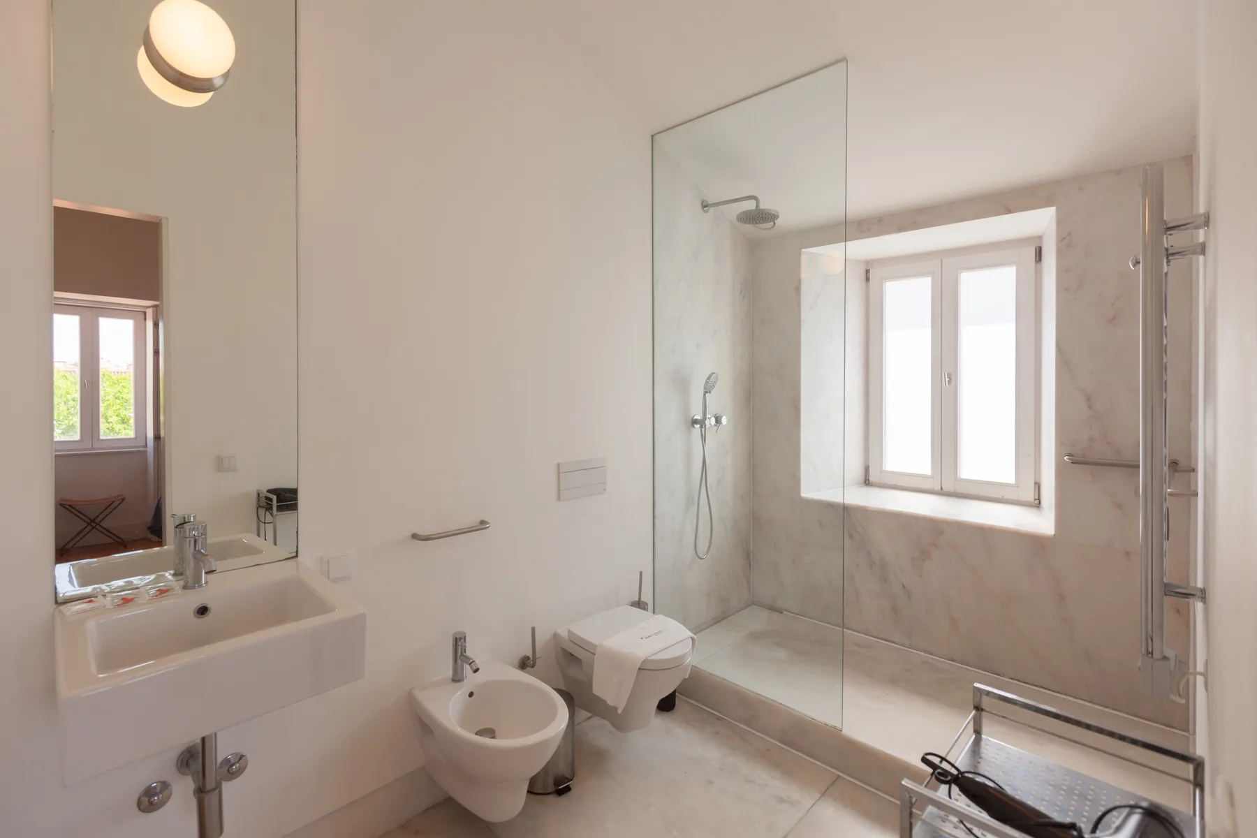 A bright bathroom with a sink, toilet, and glass shower.
