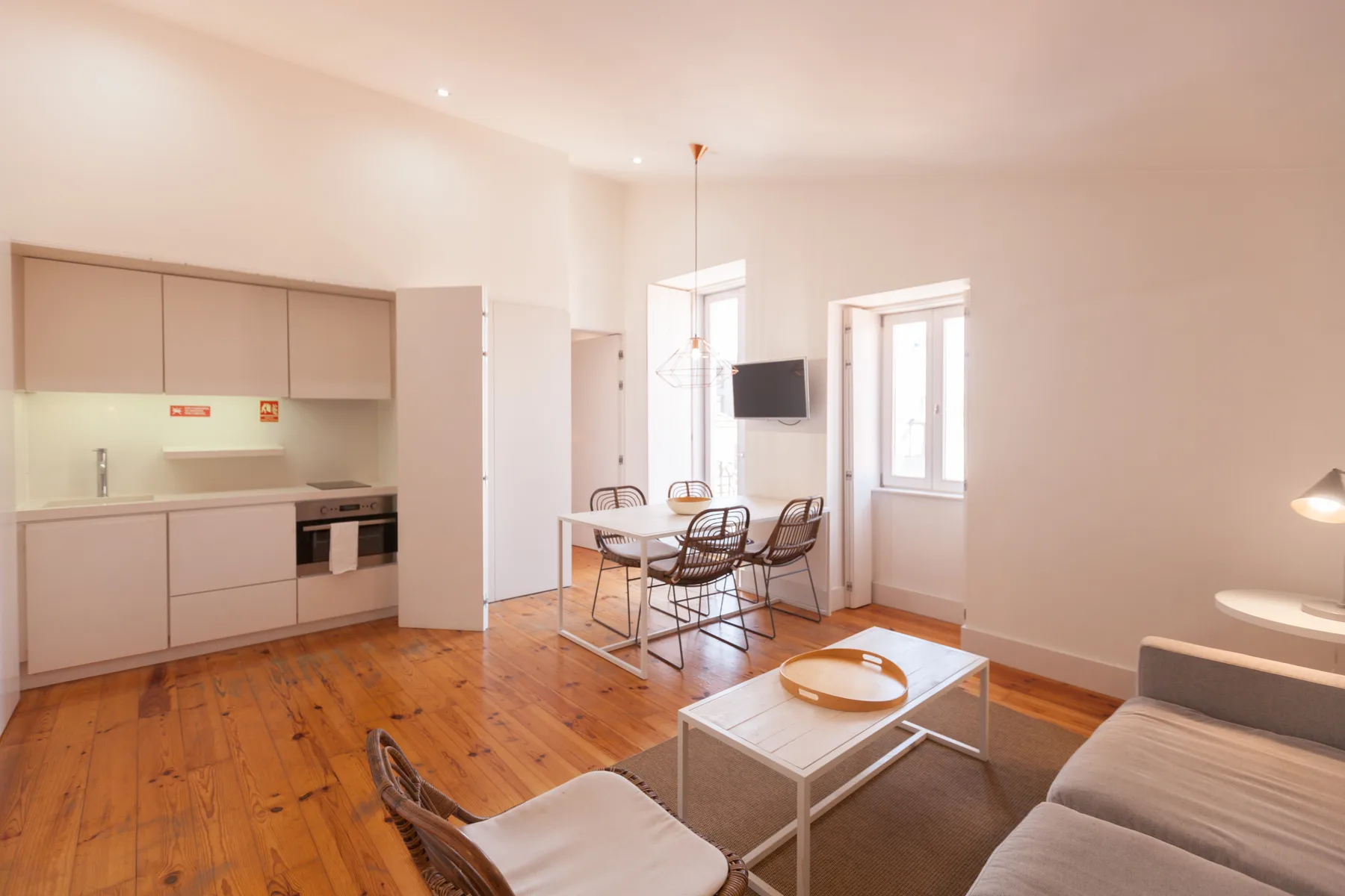 A bright living and dining area with a kitchenette, table, and seating.