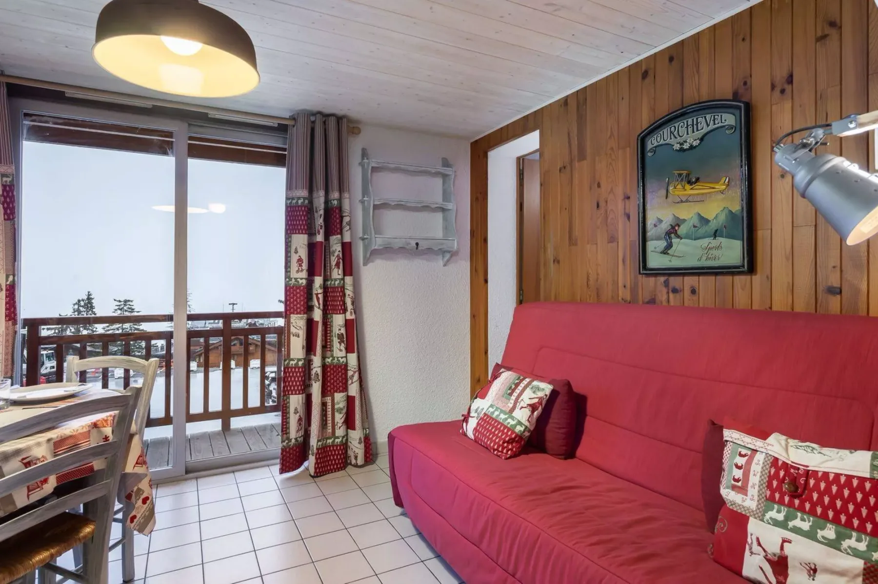 A living room with red seating beside a balcony and a large window.