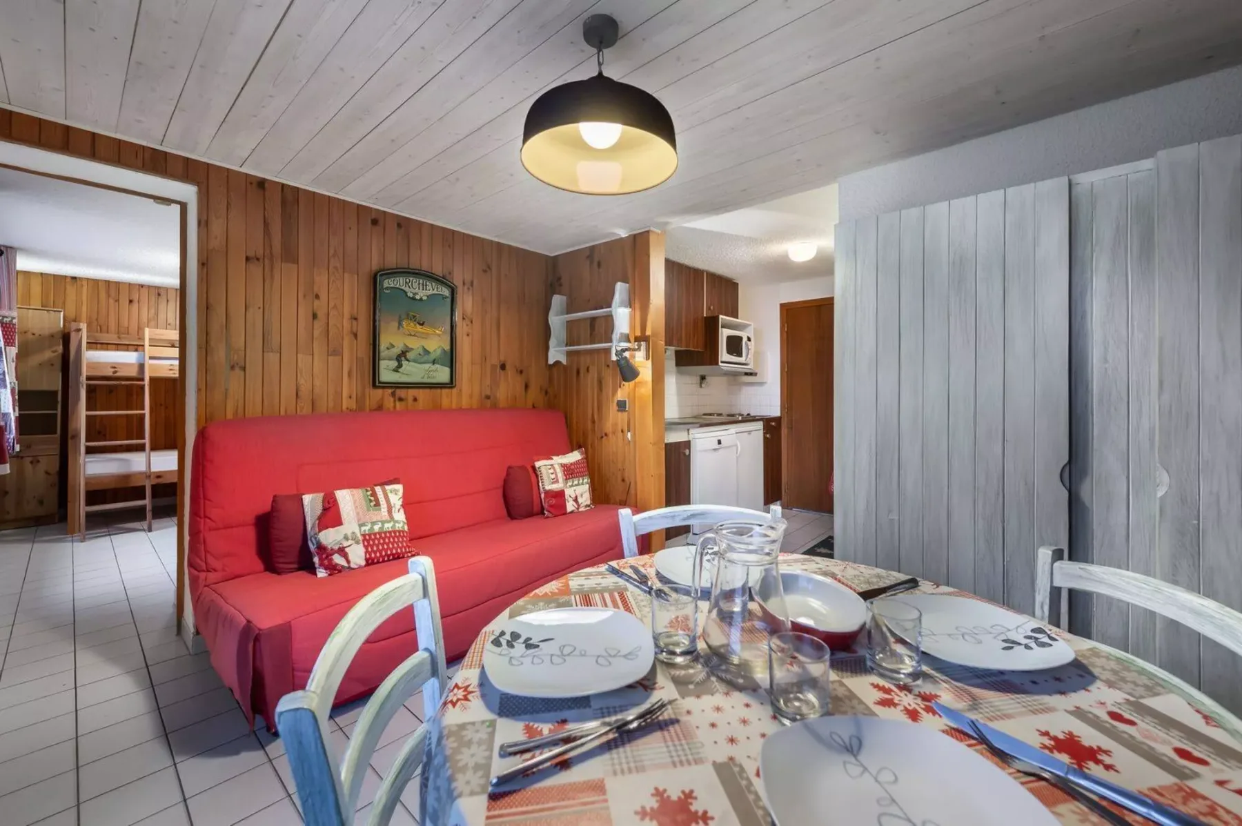 A dining area with a red sofa and a table set with plates and glasses.