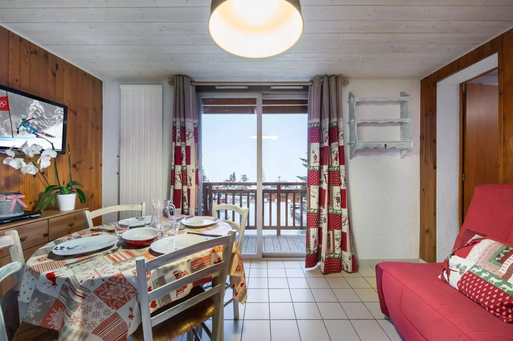 A dining area with a set table and a window opening onto a balcony.