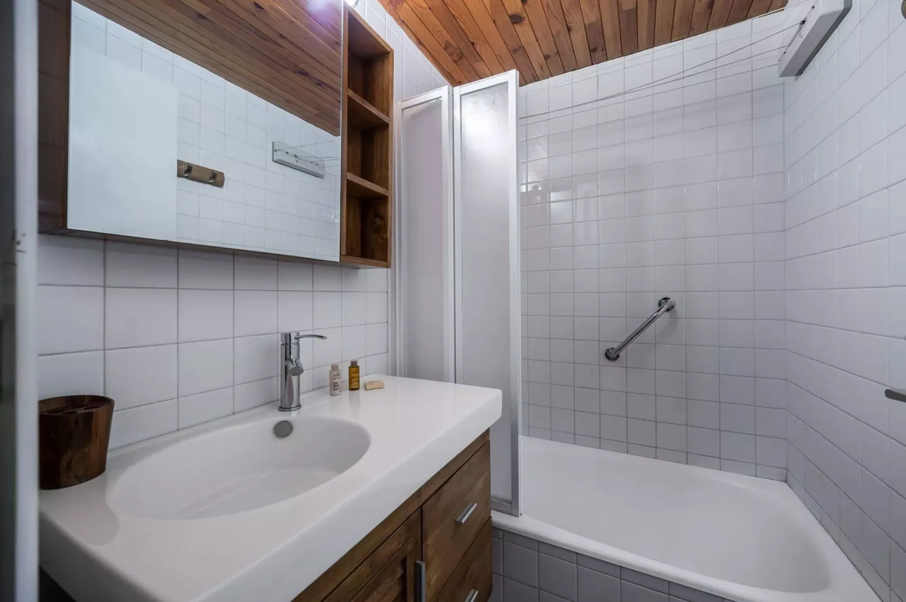 A tiled bathroom with a sink, vanity, and bathtub.