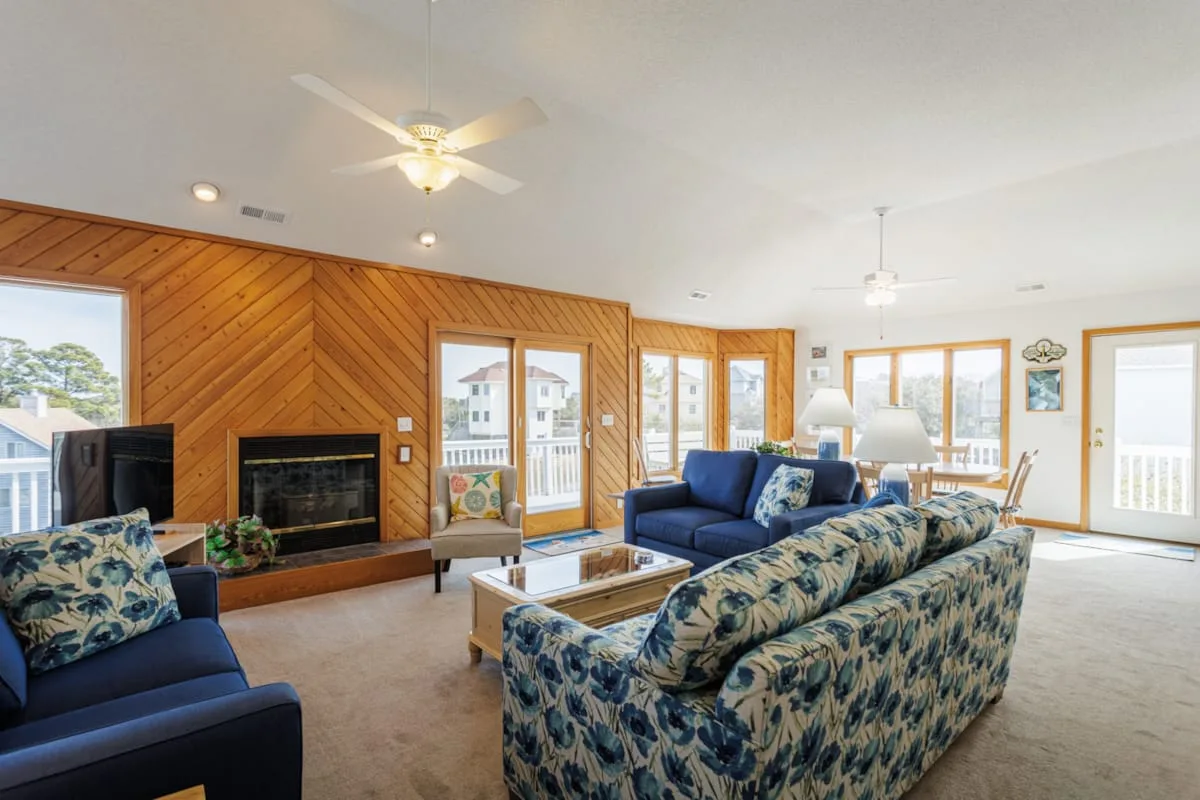 Una sala de estar con asientos azules, una chimenea y grandes ventanas.