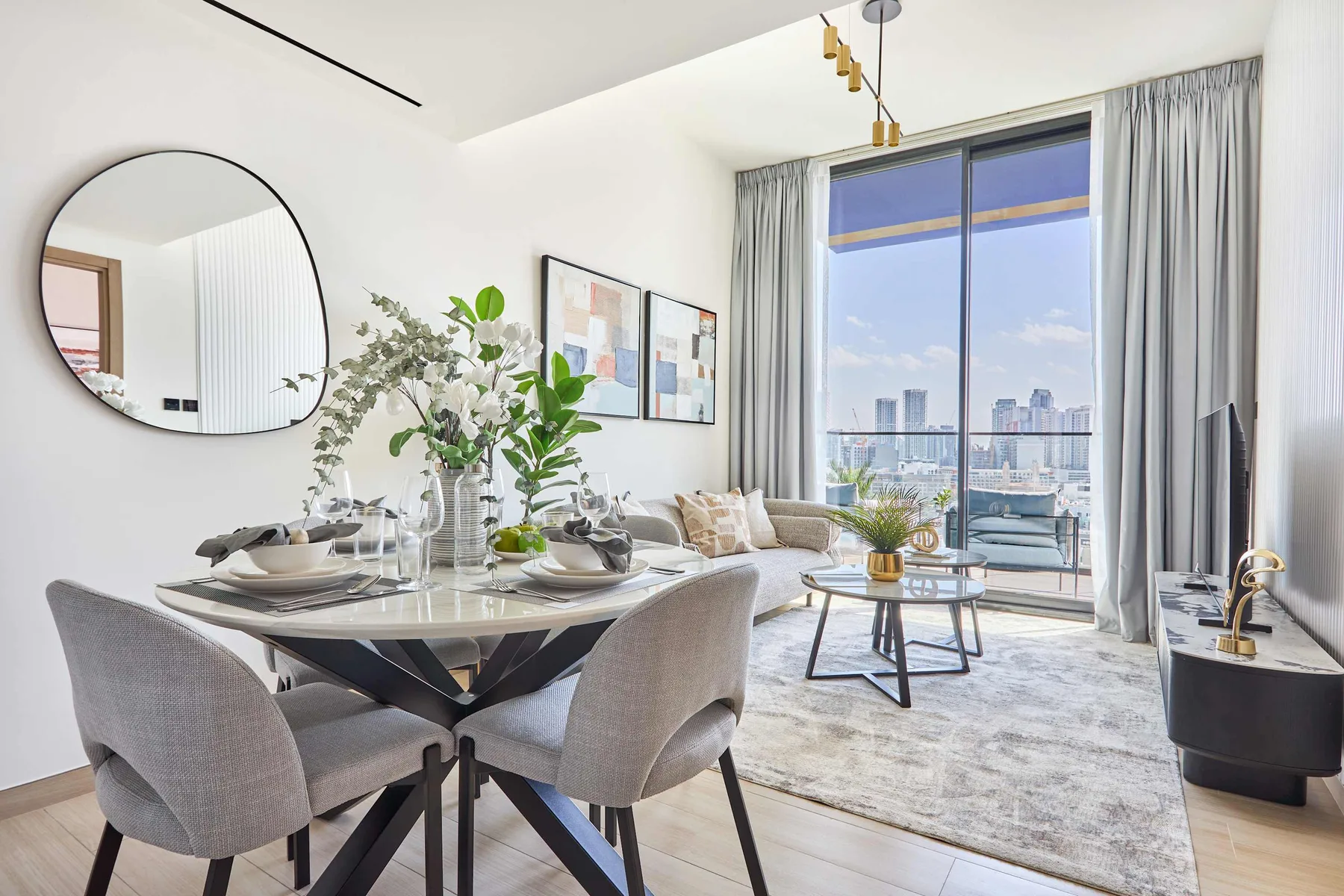 A bright open-plan living and dining area with large windows and a city view.