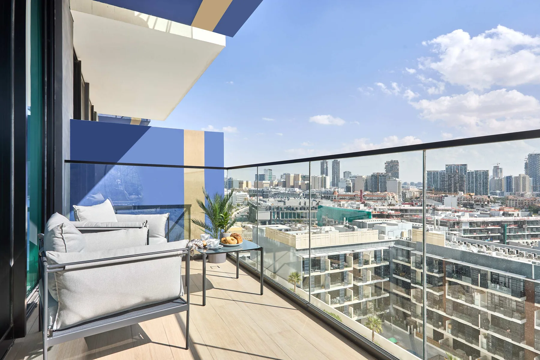 A balcony seating area overlooks a city skyline under a partly cloudy sky.