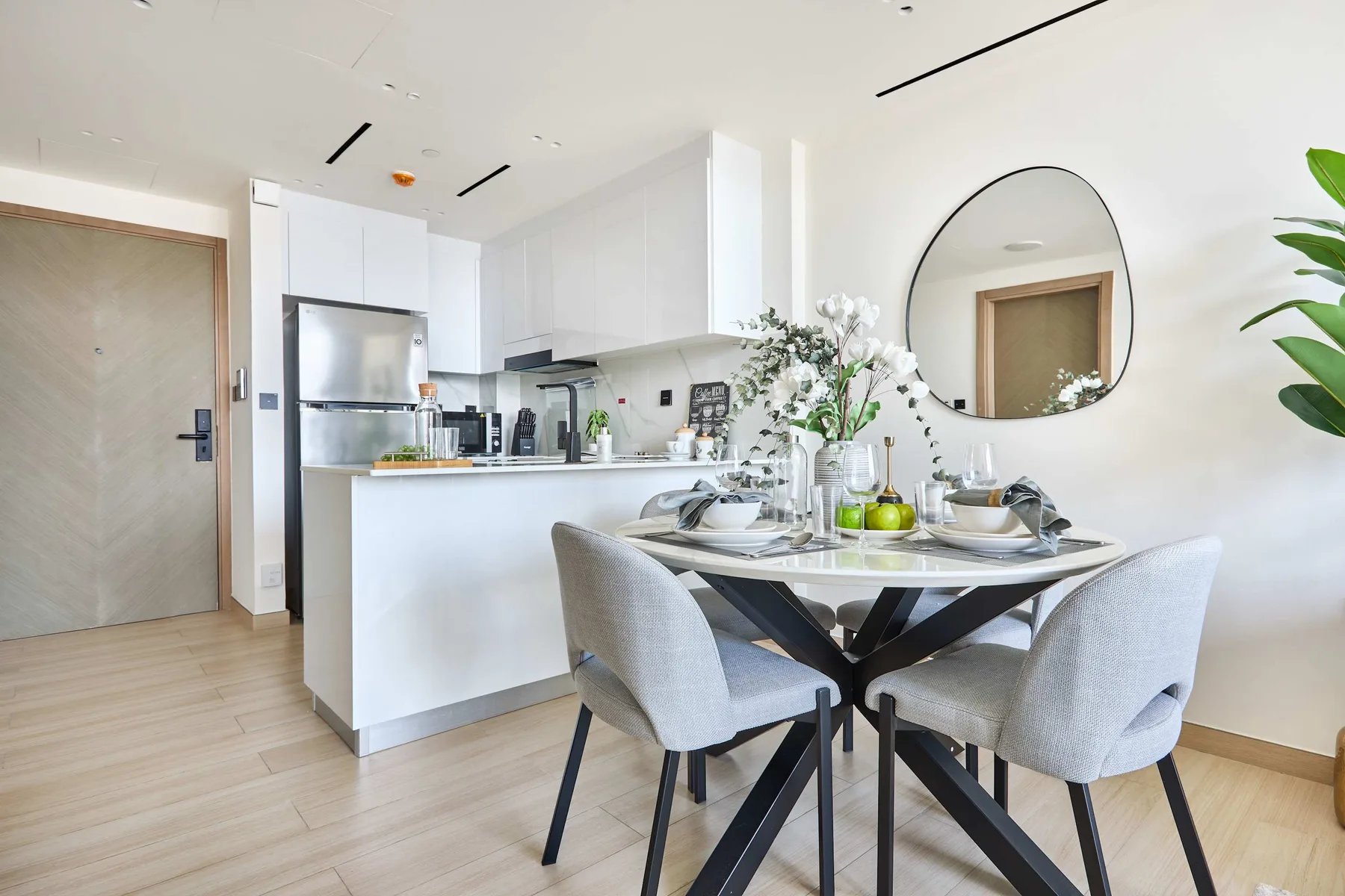 A bright dining area with a set table beside an open kitchen.