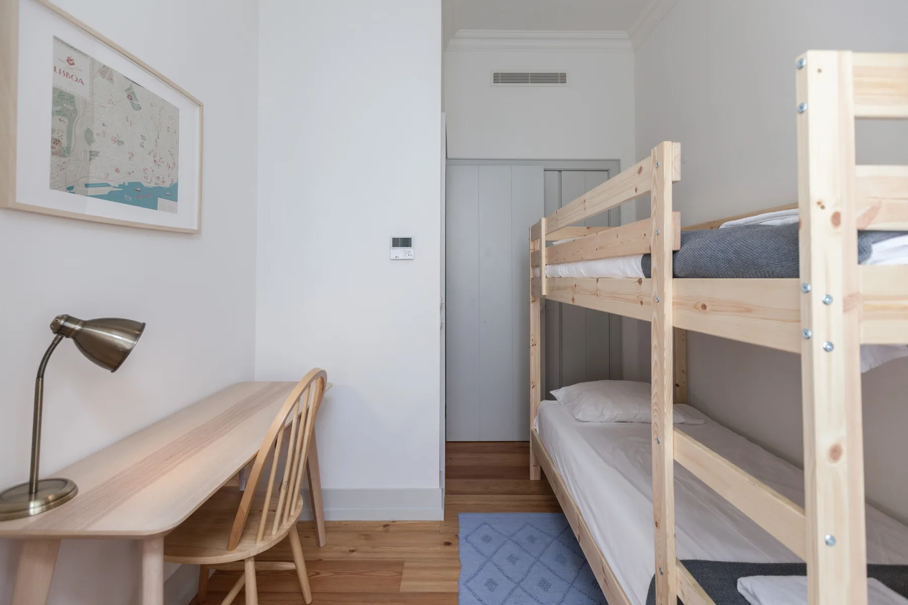 A bedroom with wooden bunk beds beside a desk and chair.