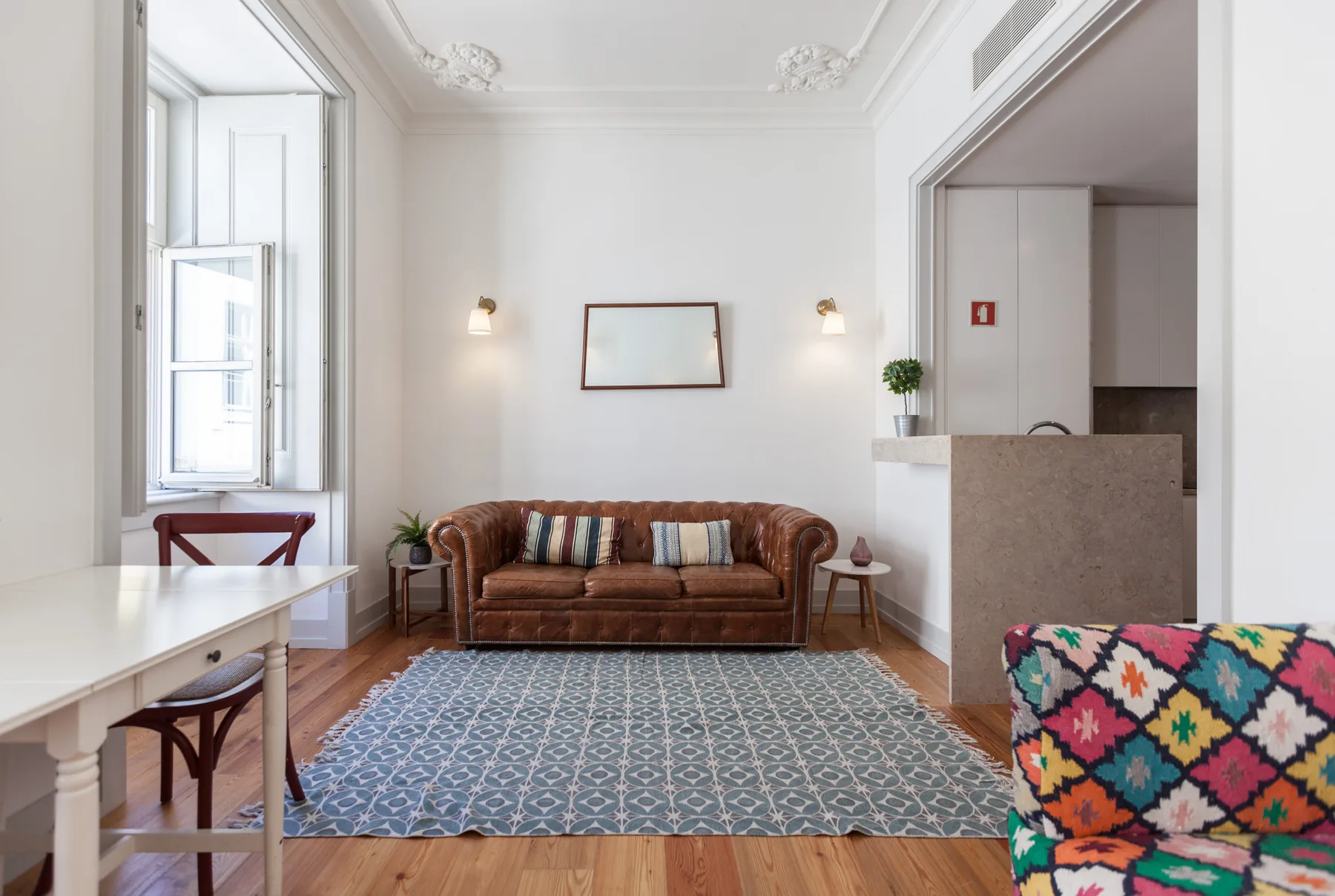 A bright living room with a brown sofa and patterned rug.
