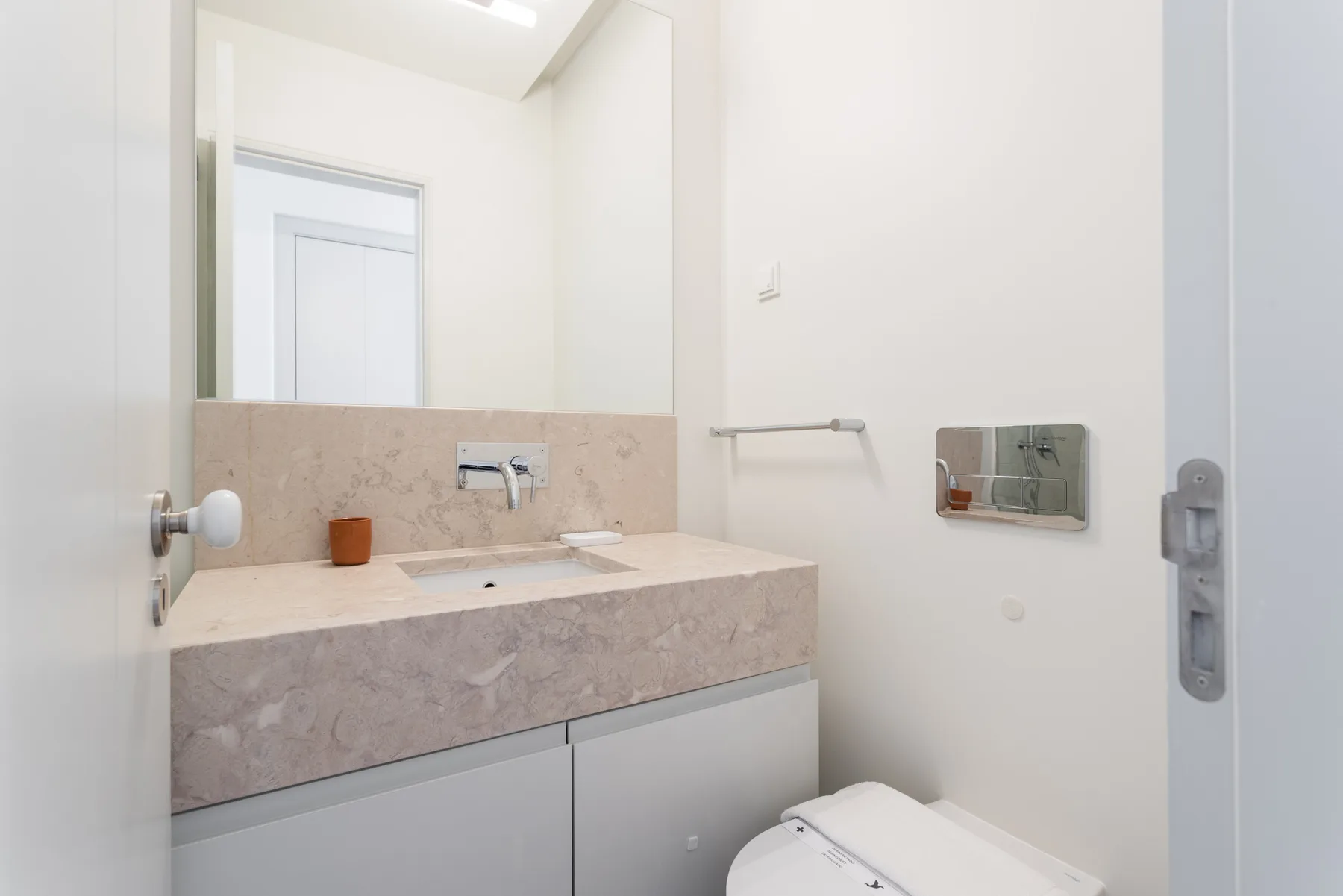 A bright bathroom with a wide vanity, mirror, and toilet.