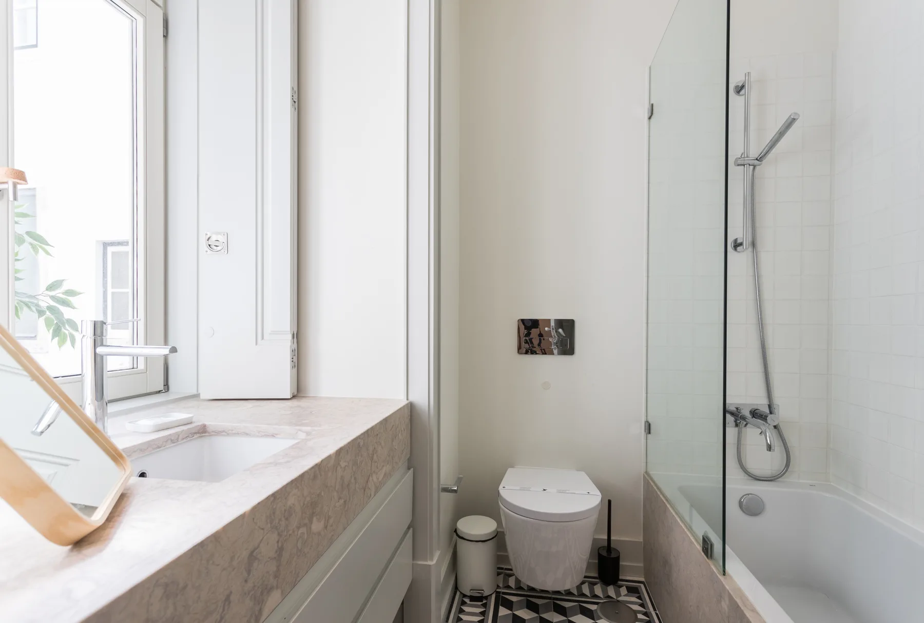 A bright bathroom with a sink beside a glass shower.