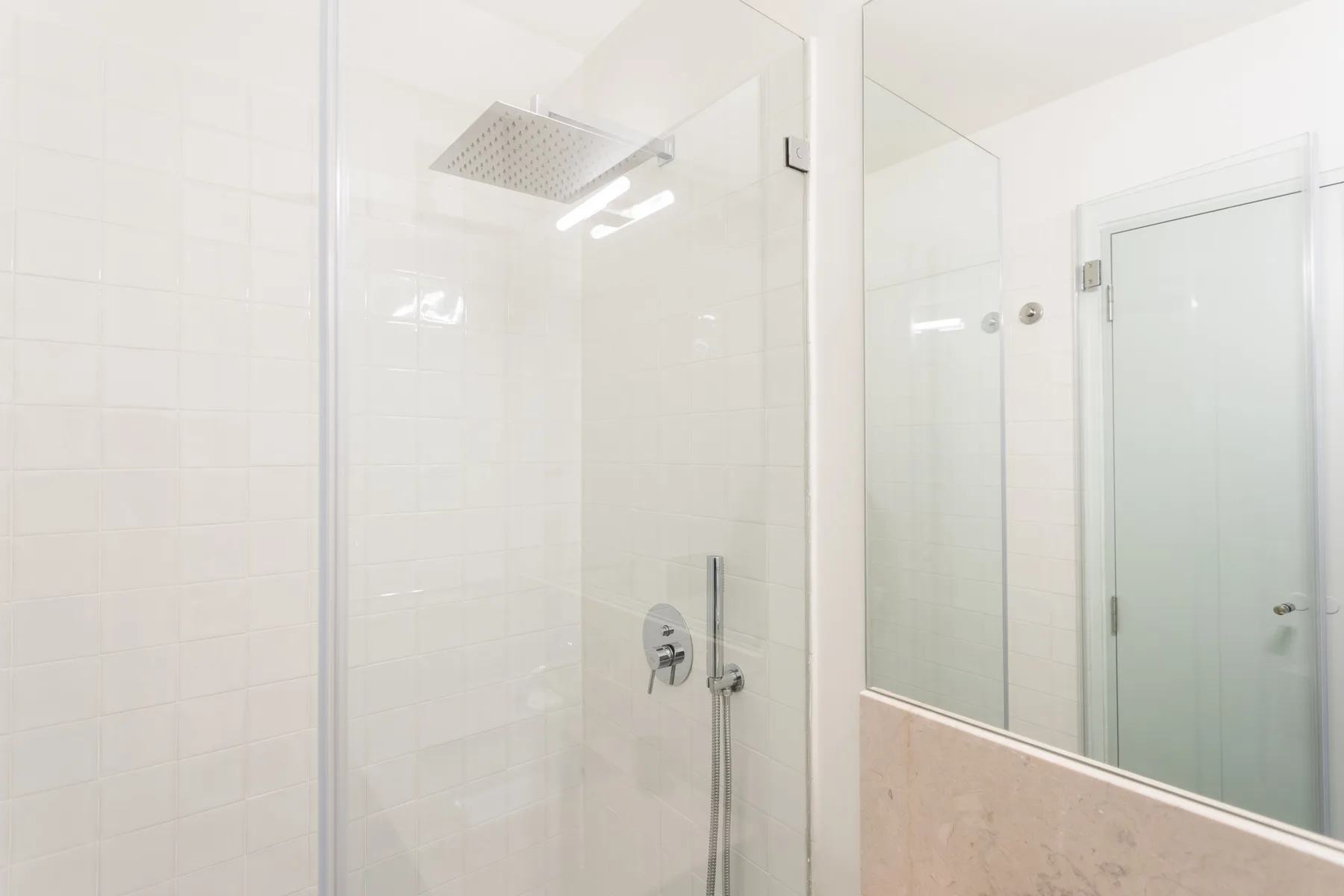 A tiled bathroom shower with a large overhead showerhead.