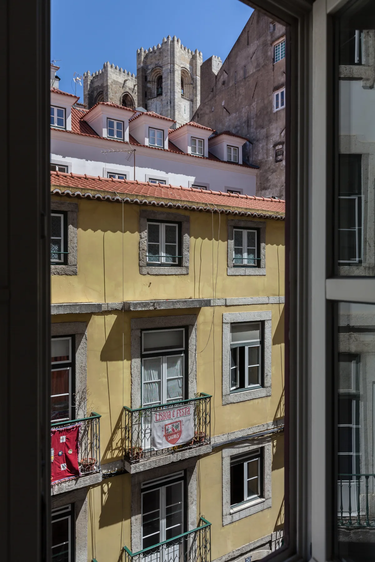 A view through a window shows neighboring buildings and a stone tower.