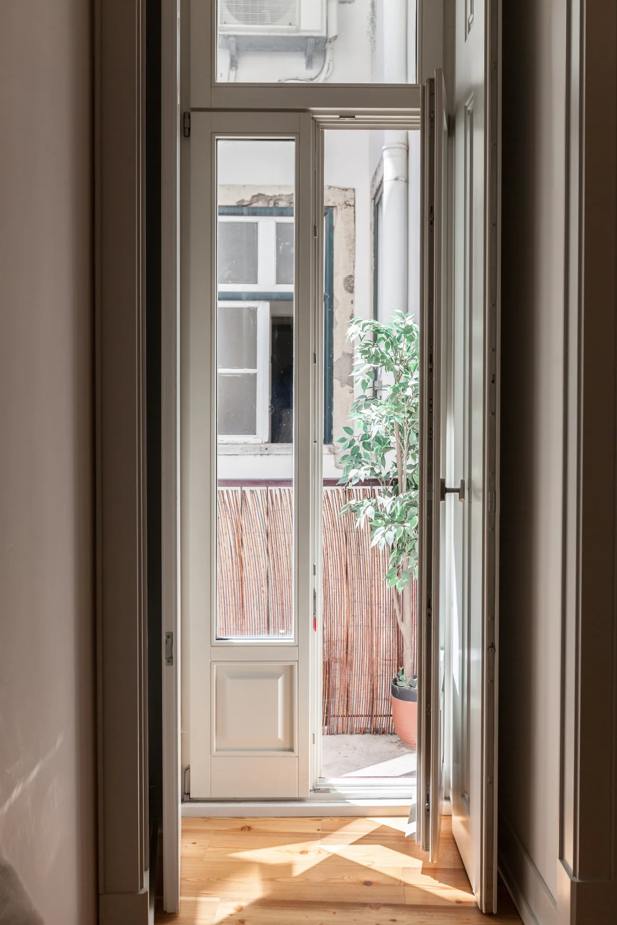 A bright room opens onto a small balcony through a glass door.