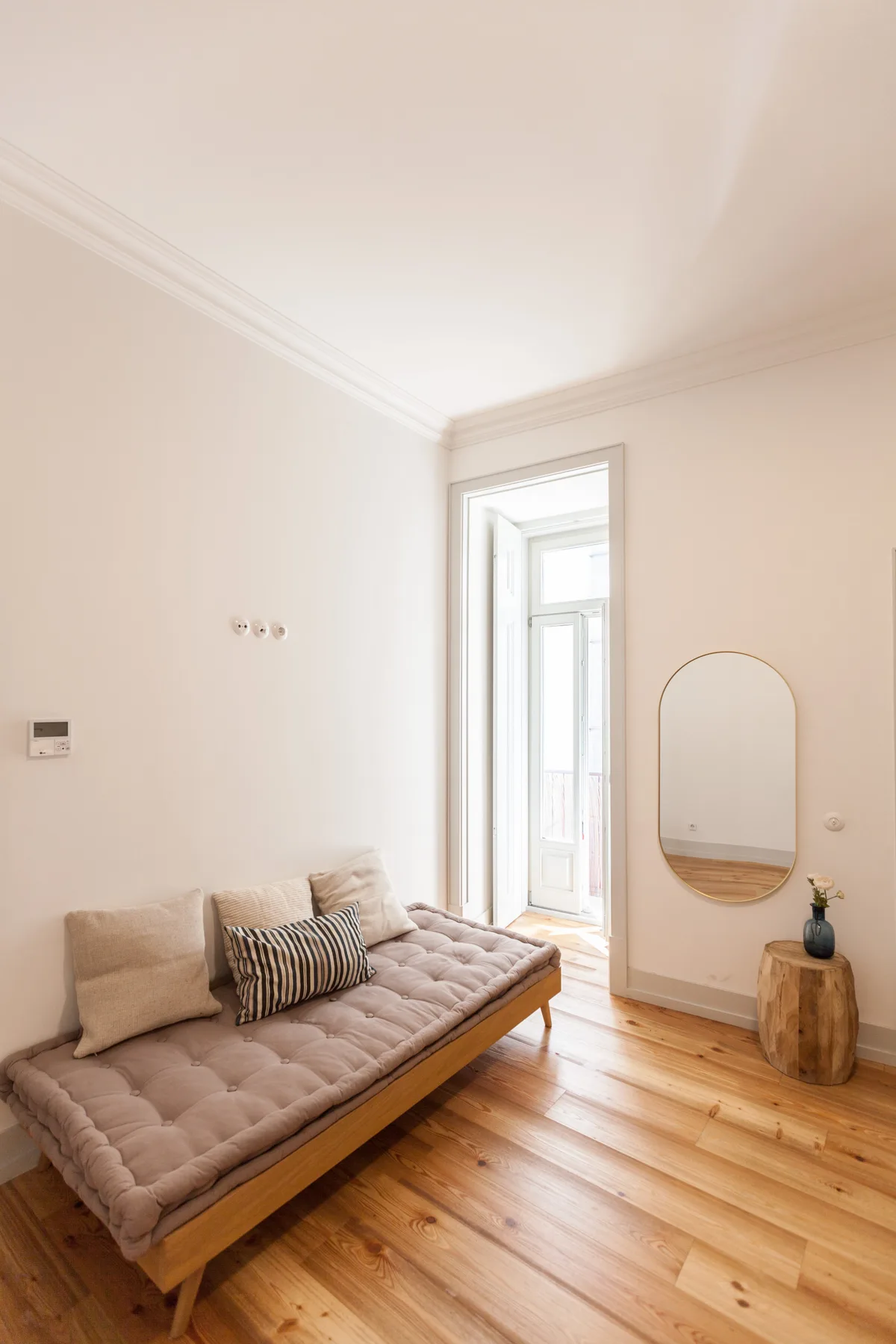 A bright sitting area with a cushioned daybed beside a tall window.