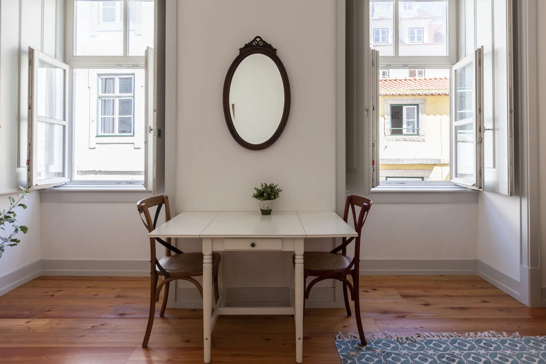 A dining area with a table and chairs between two open windows.