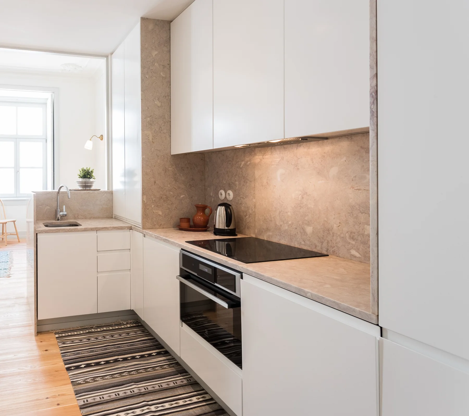 A bright modern kitchen with white cabinets, a cooktop, and a countertop.