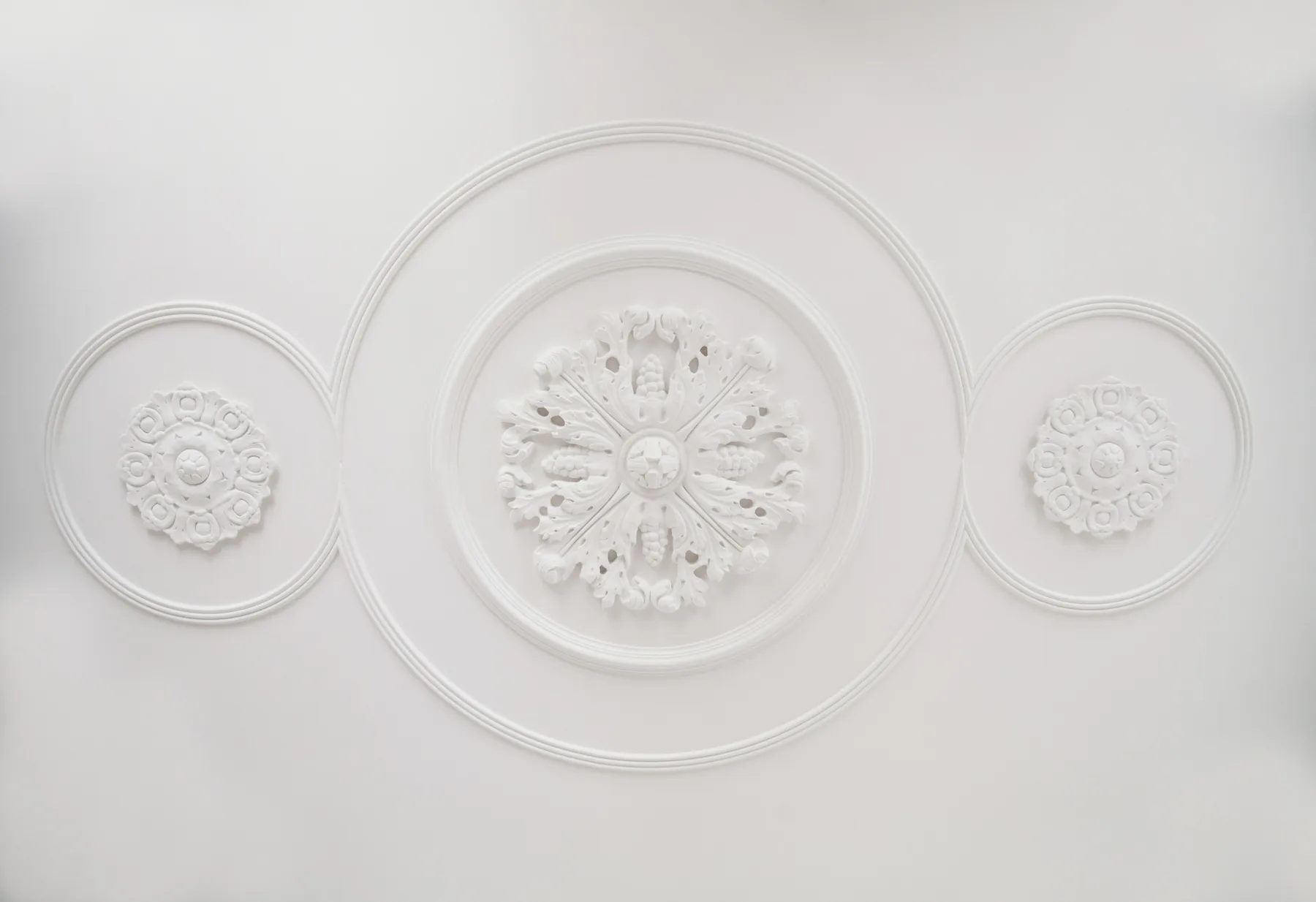 A white ceiling with three ornate circular decorative reliefs.