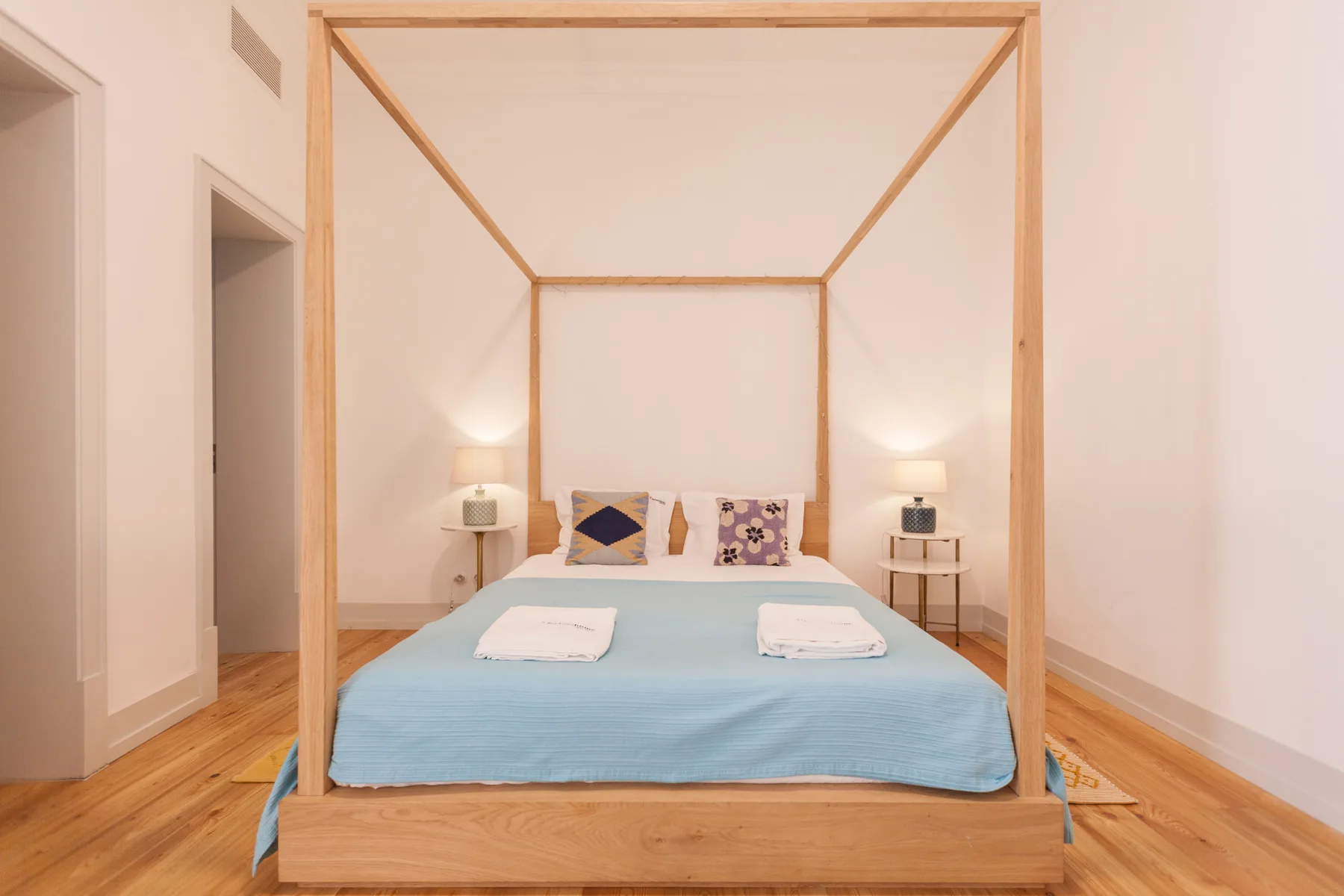 A bedroom with a wooden four-poster bed dressed in blue bedding.