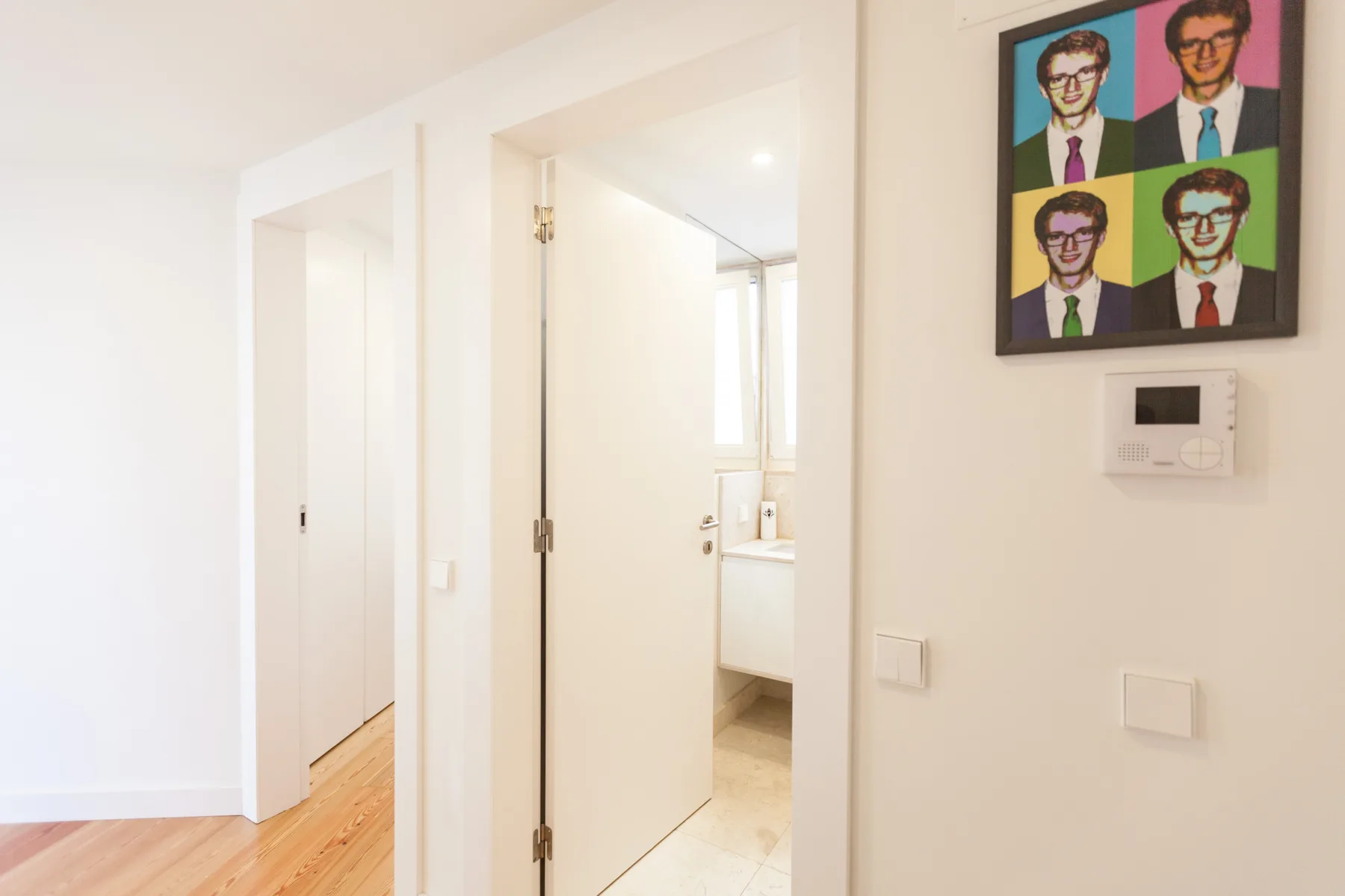 Un pasillo interior luminoso se abre a un baño a través de una puerta.