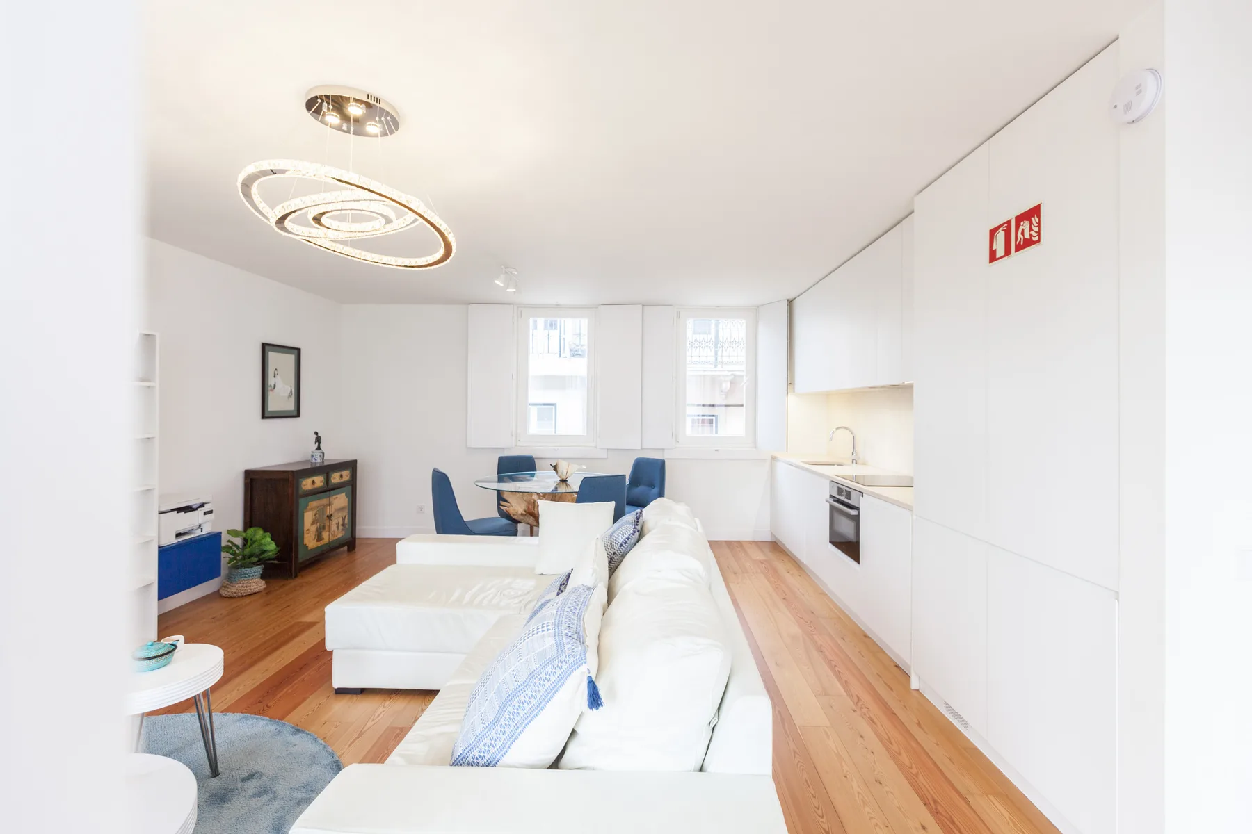 Una luminosa sala de estar diáfana con zona de descanso, mesa de comedor y cocina compacta.