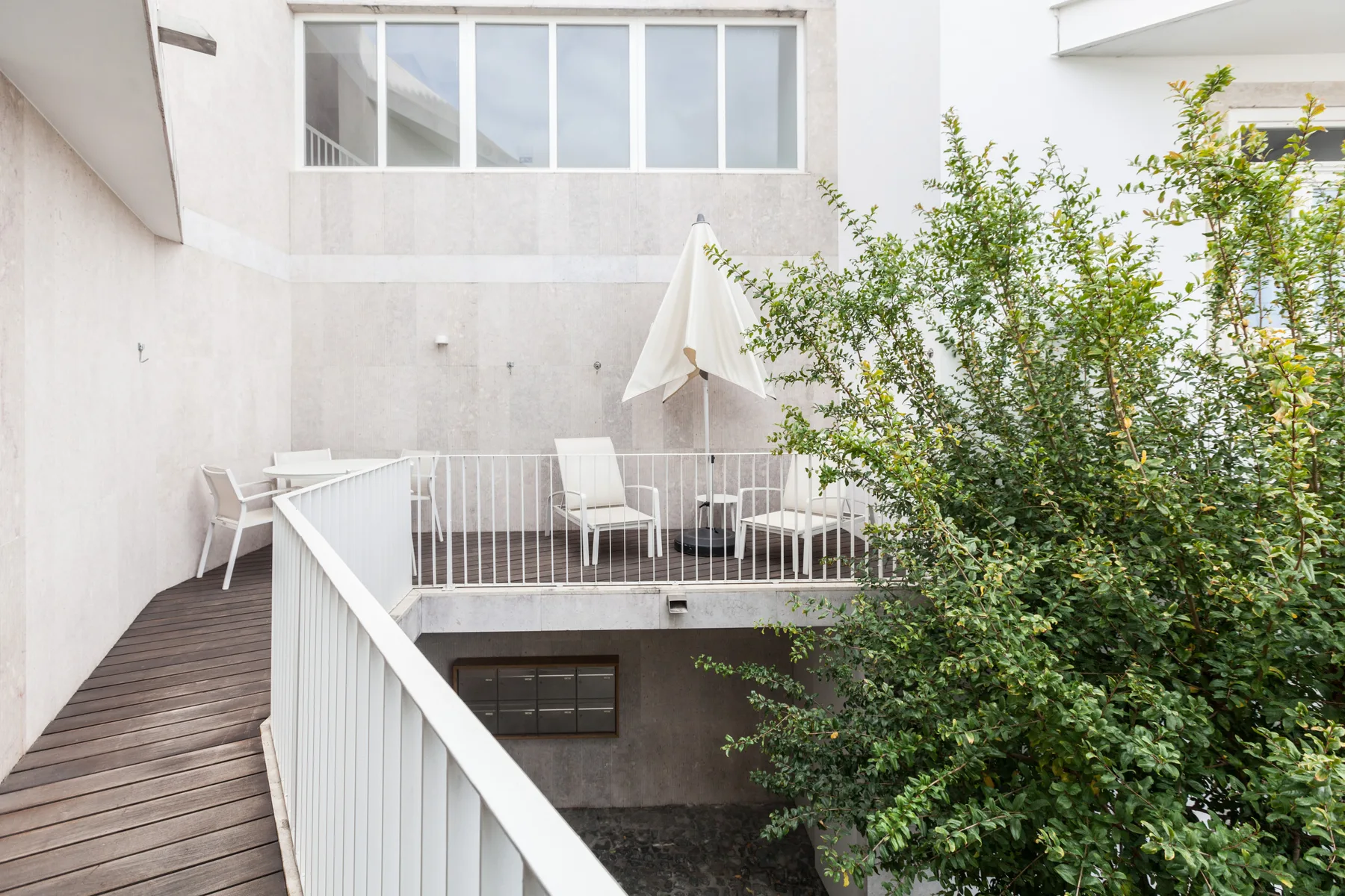 Un patio con asientos al aire libre y una sombrilla abierta da a un patio frondoso.