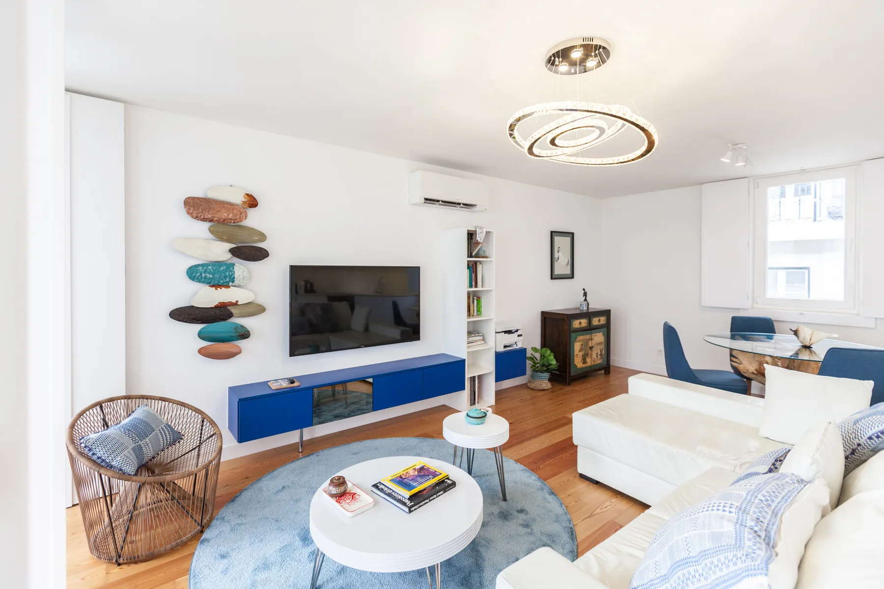A bright living room with a television, white seating, and a blue media console.