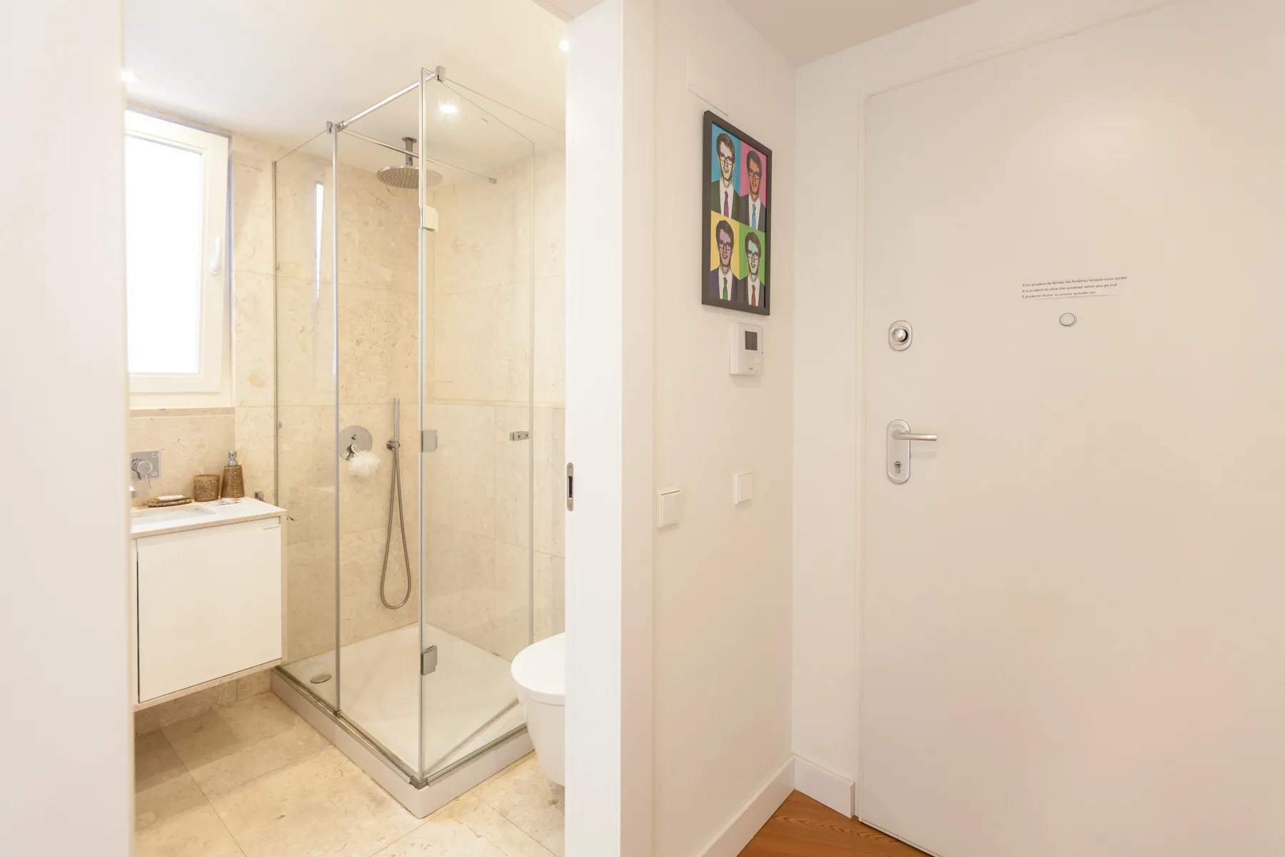 Un baño luminoso con una ducha de cristal y una ventana.