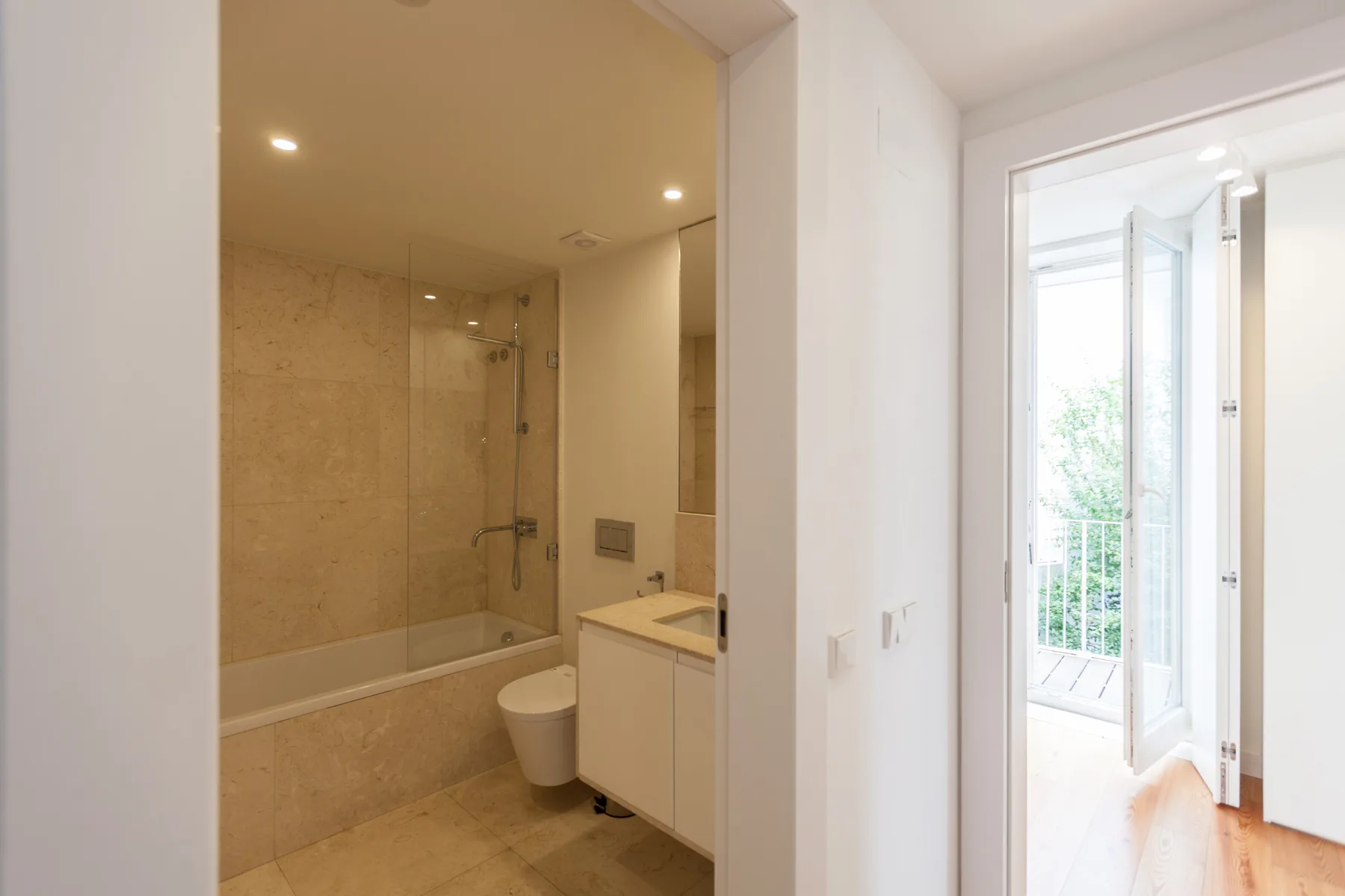 Un baño con bañera y lavabo se abre a una habitación luminosa.