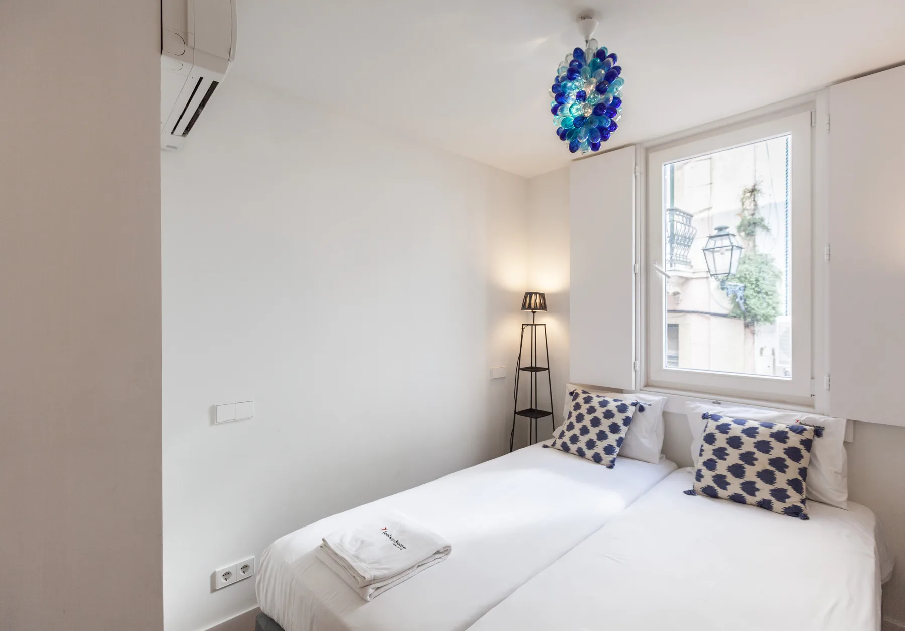 Un dormitorio luminoso con ropa de cama blanca y almohadas estampadas azules.