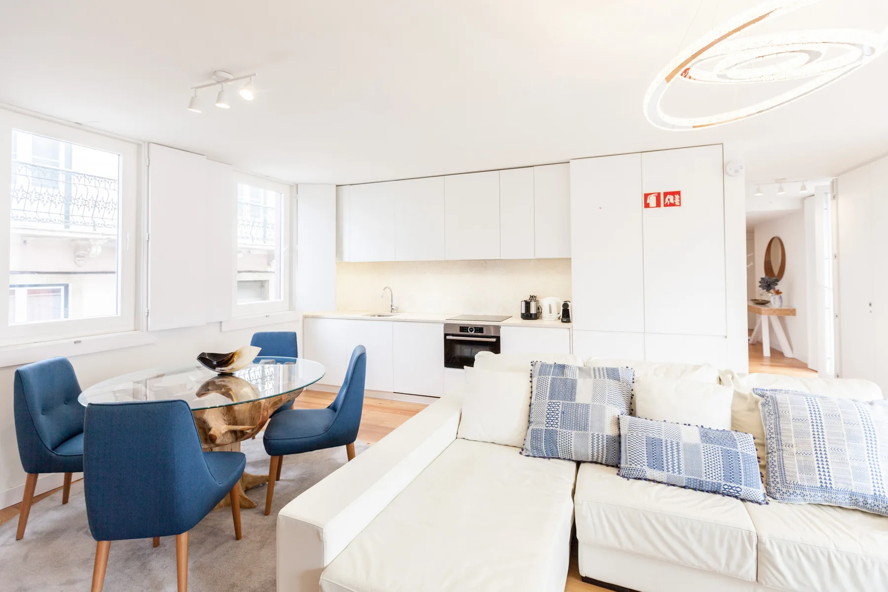 Una luminosa sala de estar y comedor de planta abierta con asientos azules y muebles blancos.