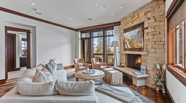 Living room with a seating area beside a stone fireplace and large windows.