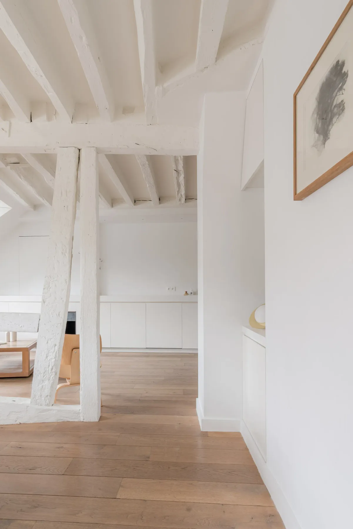 A bright interior hallway opens into a living area with exposed white beams.