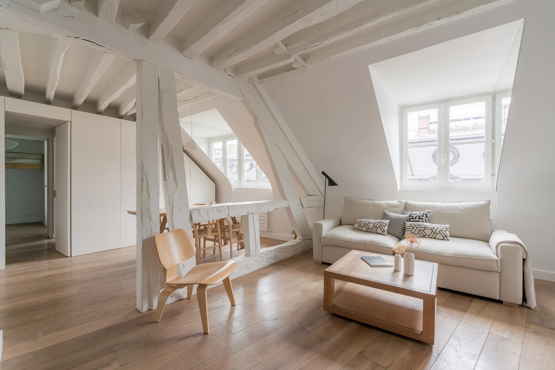 A bright attic living room with seating and a small dining table.