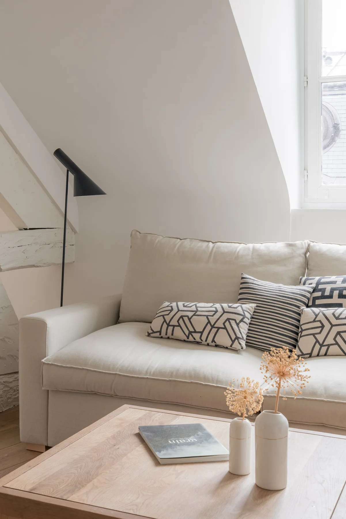 A bright living area with a light-colored sofa and a wooden coffee table.