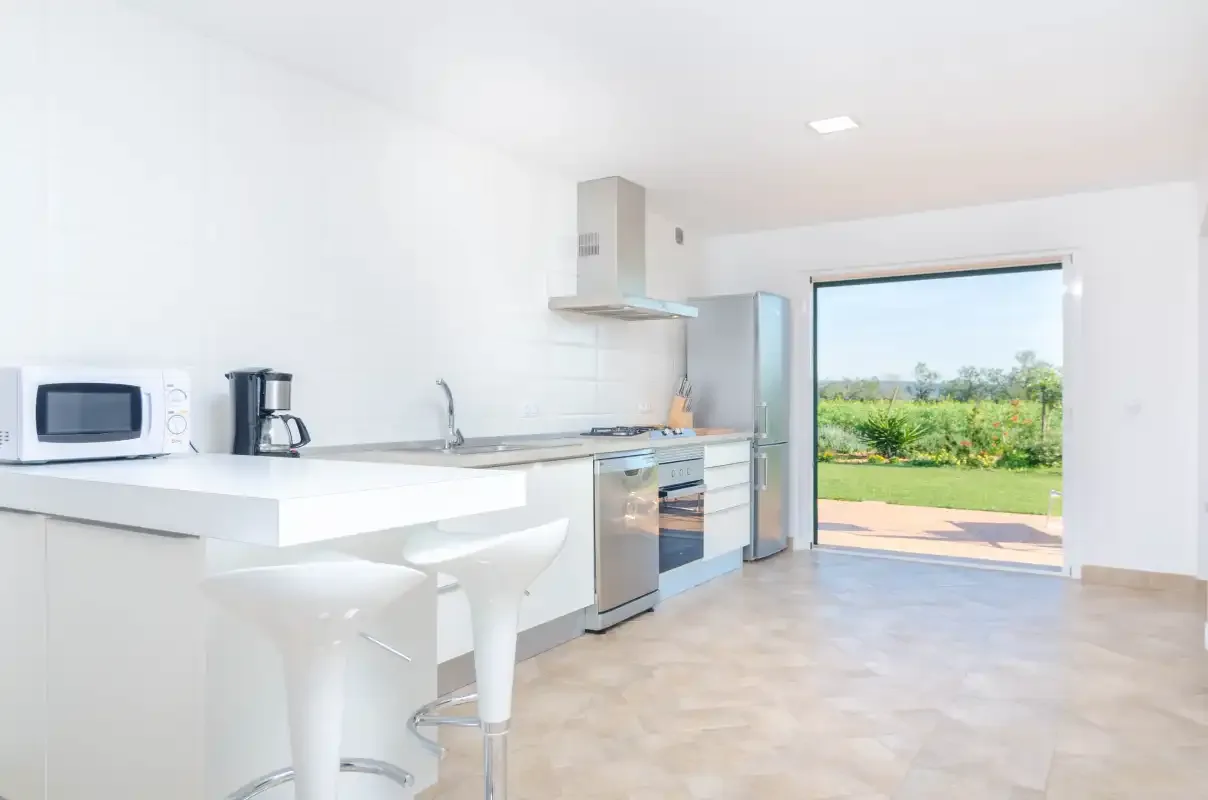A bright kitchen with a counter and an open doorway to the garden.