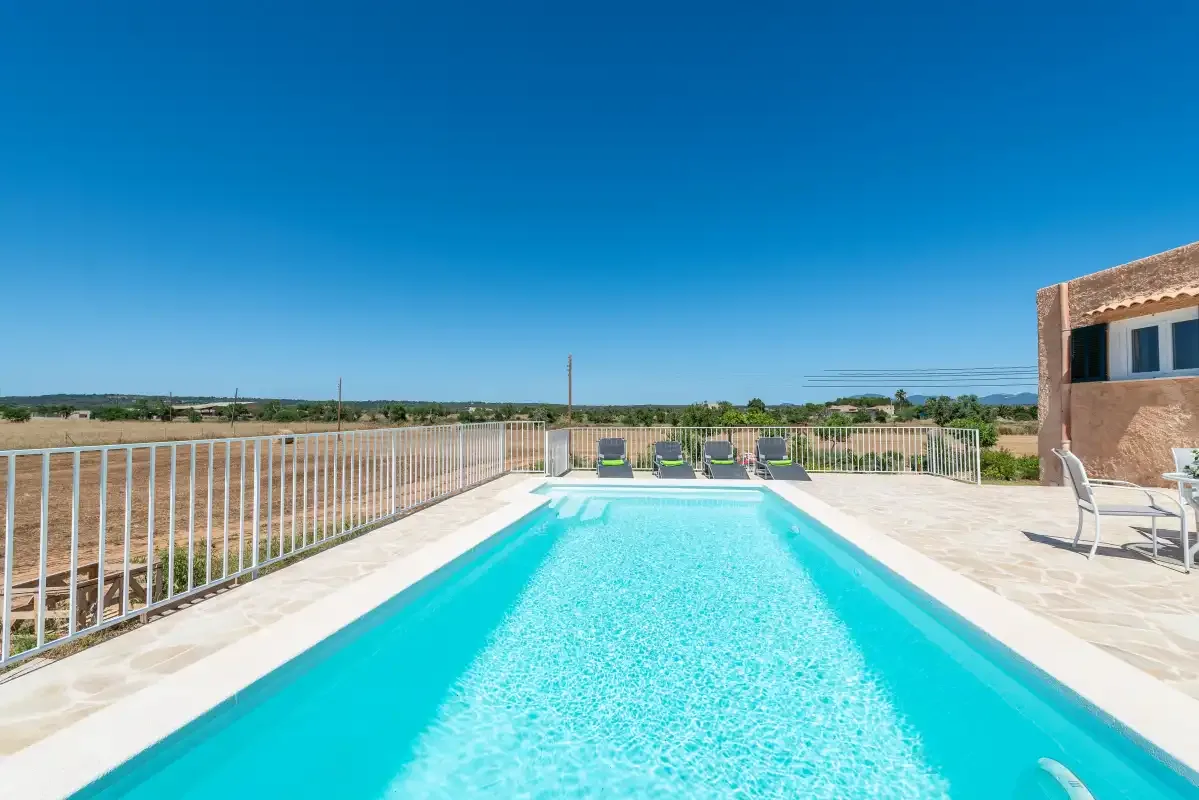 An outdoor swimming pool with lounge seating and open countryside beyond.