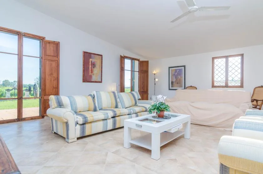 A bright living room with striped seating, a coffee table, and large windows.