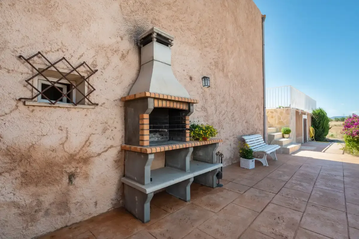 A paved outdoor patio with a built-in barbecue and seating.